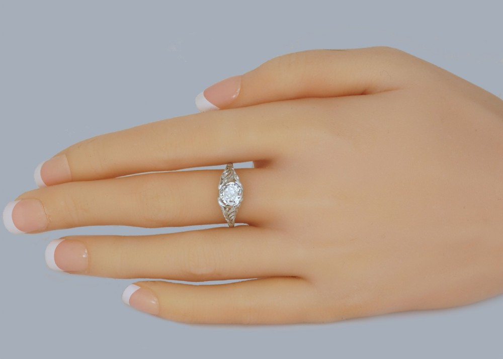 A top-down view of an Edwardian platinum solitaire ring featuring a central old cut diamond set in carved pierced shoulders. View XIV