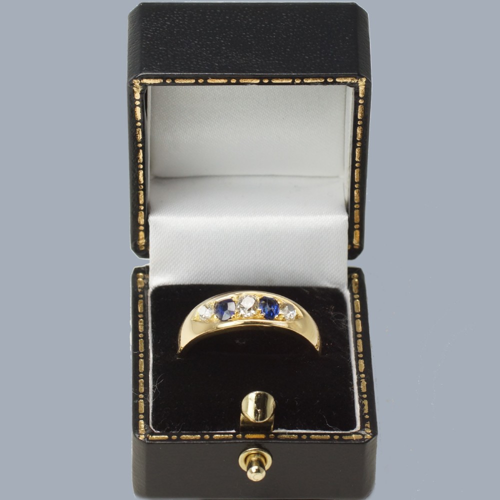 A late Victorian 18ct gold boat ring set horizontally with alternating blue sapphires and white diamonds. View X