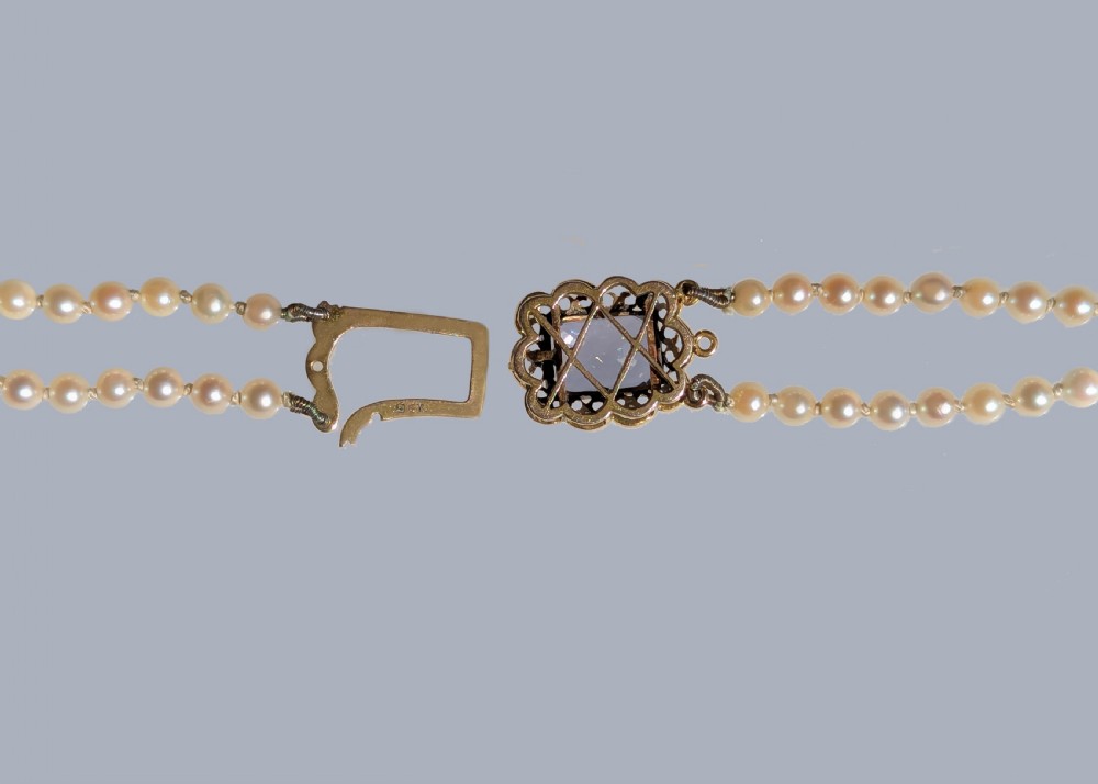 A double strand cream pearl necklace featuring an ornate 9ct gold clasp set with a rectangular step-cut amethyst. View IV