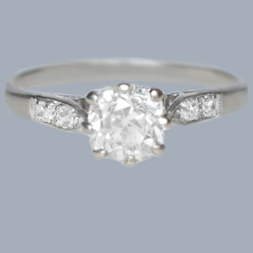 An Edwardian style diamond solitaire ring featuring a round old European cut centre stone with accent diamonds set into the shoulders.