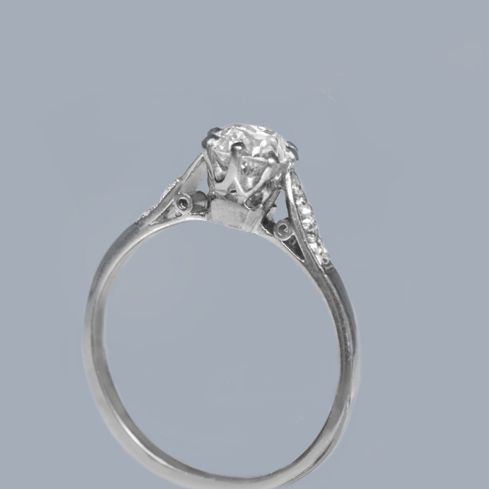 An Edwardian style diamond solitaire ring featuring a round old European cut centre stone with accent diamonds set into the shoulders. View V