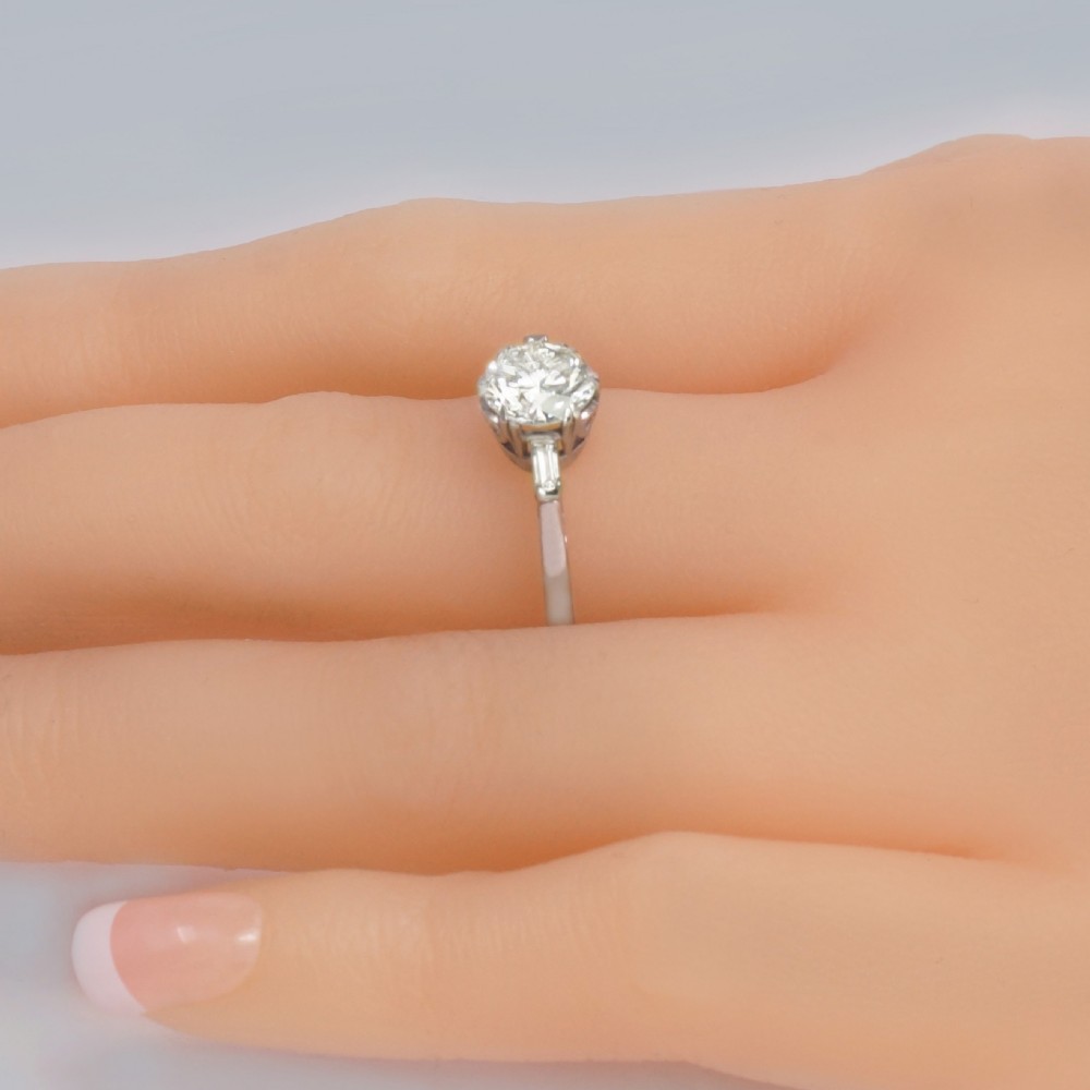 An Art Deco platinum solitaire ring featuring a round brilliant cut diamond flanked by stepped baguette cut shoulder stones. View III