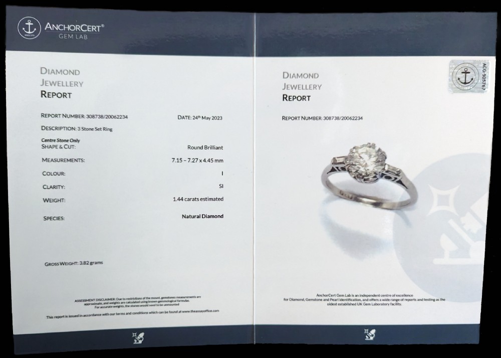 An Art Deco platinum solitaire ring featuring a round brilliant cut diamond flanked by stepped baguette cut shoulder stones. View VI