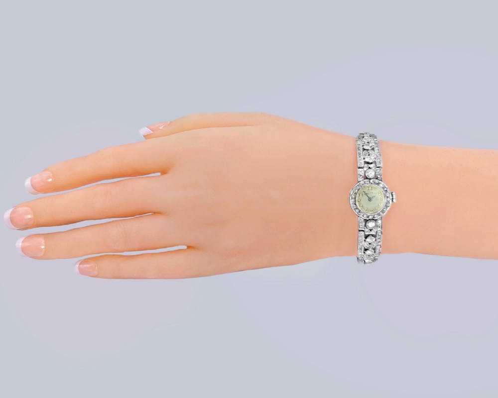 A mid-century Tissot ladies wristwatch featuring a circular cream dial with gold-tone Arabic numerals, set within a platinum bezel and articulated bracelet fully encrusted with round diamonds. View III