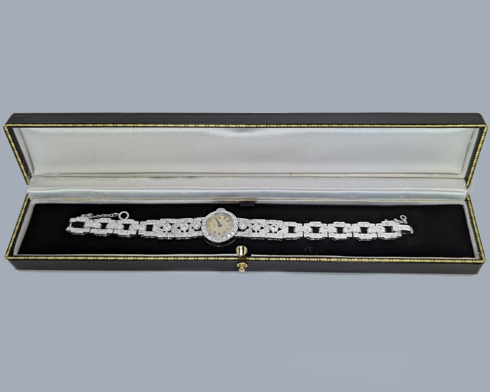A mid-century Tissot ladies wristwatch featuring a circular cream dial with gold-tone Arabic numerals, set within a platinum bezel and articulated bracelet fully encrusted with round diamonds. View IX