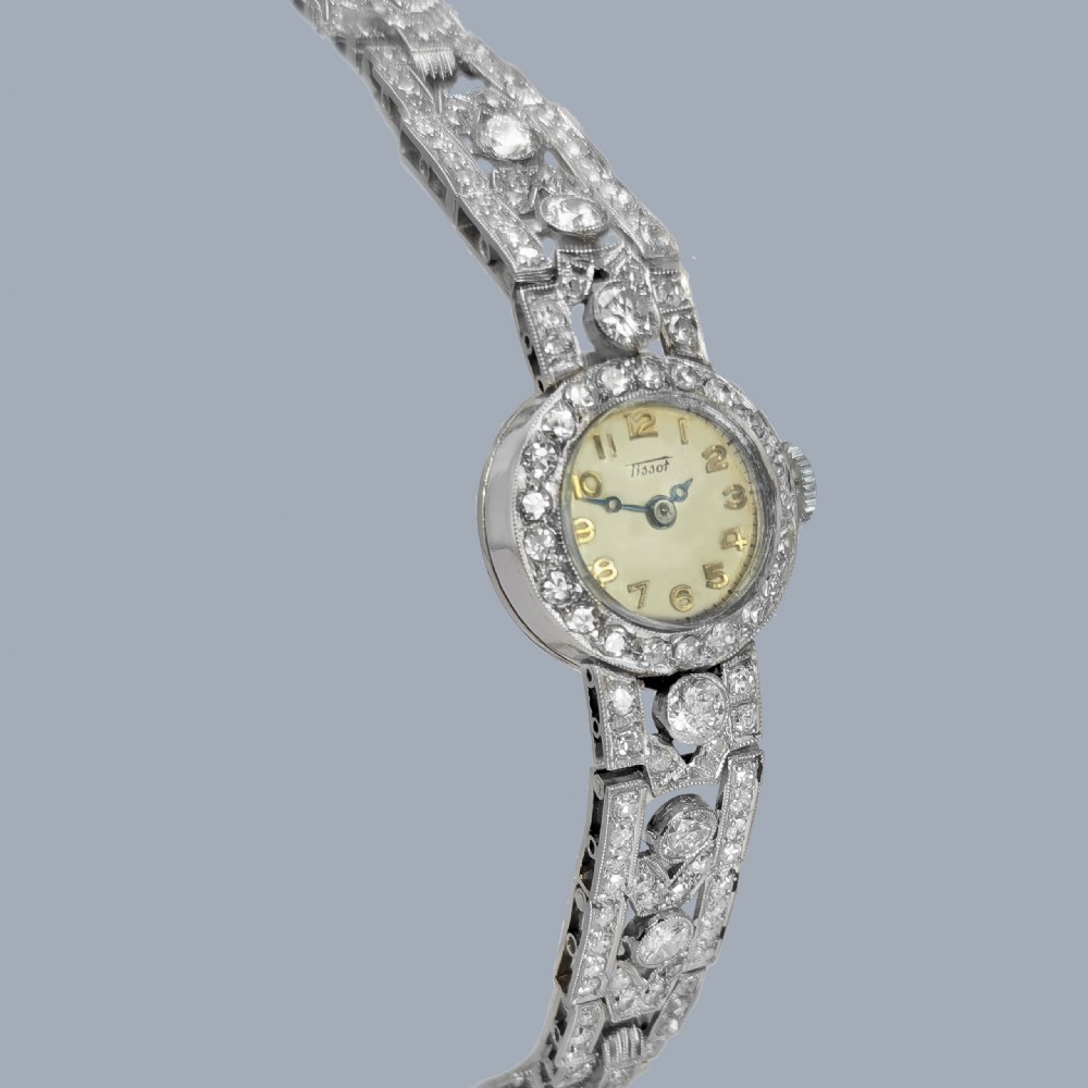 A mid-century Tissot ladies wristwatch featuring a circular cream dial with gold-tone Arabic numerals, set within a platinum bezel and articulated bracelet fully encrusted with round diamonds. View X
