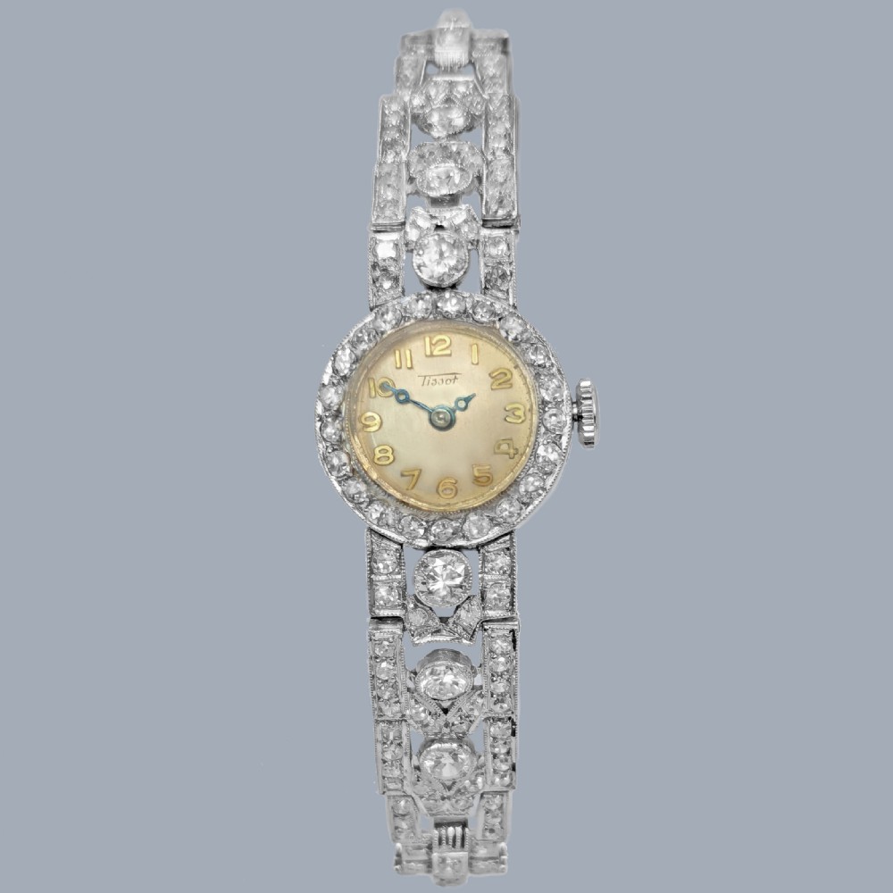 A mid-century Tissot ladies wristwatch featuring a circular cream dial with gold-tone Arabic numerals, set within a platinum bezel and articulated bracelet fully encrusted with round diamonds. View XI