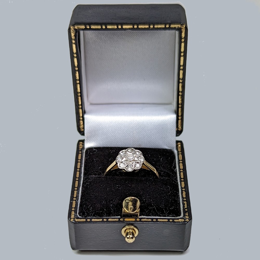 An 18ct yellow gold ring featuring a central diamond surrounded by a cluster of smaller round diamonds in a floral daisy pattern. View VIII