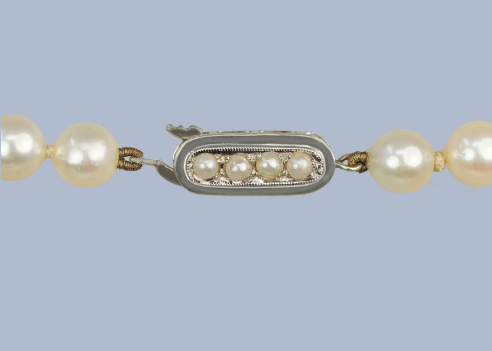 A continuous fifty-inch strand of uniform cream cultured pearls with a rectangular nine-carat gold clasp inset with small pearls. View II