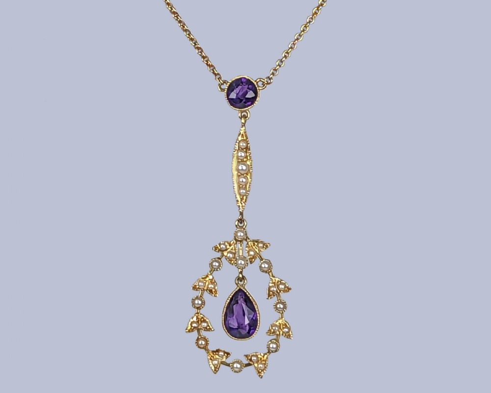 A Victorian gold pendant necklace featuring a central teardrop amethyst suspended within a seed pearl foliate wreath, attached to a gold chain. View II