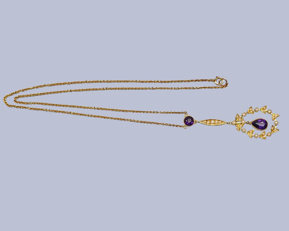 A Victorian gold pendant necklace featuring a central teardrop amethyst suspended within a seed pearl foliate wreath, attached to a gold chain. View III