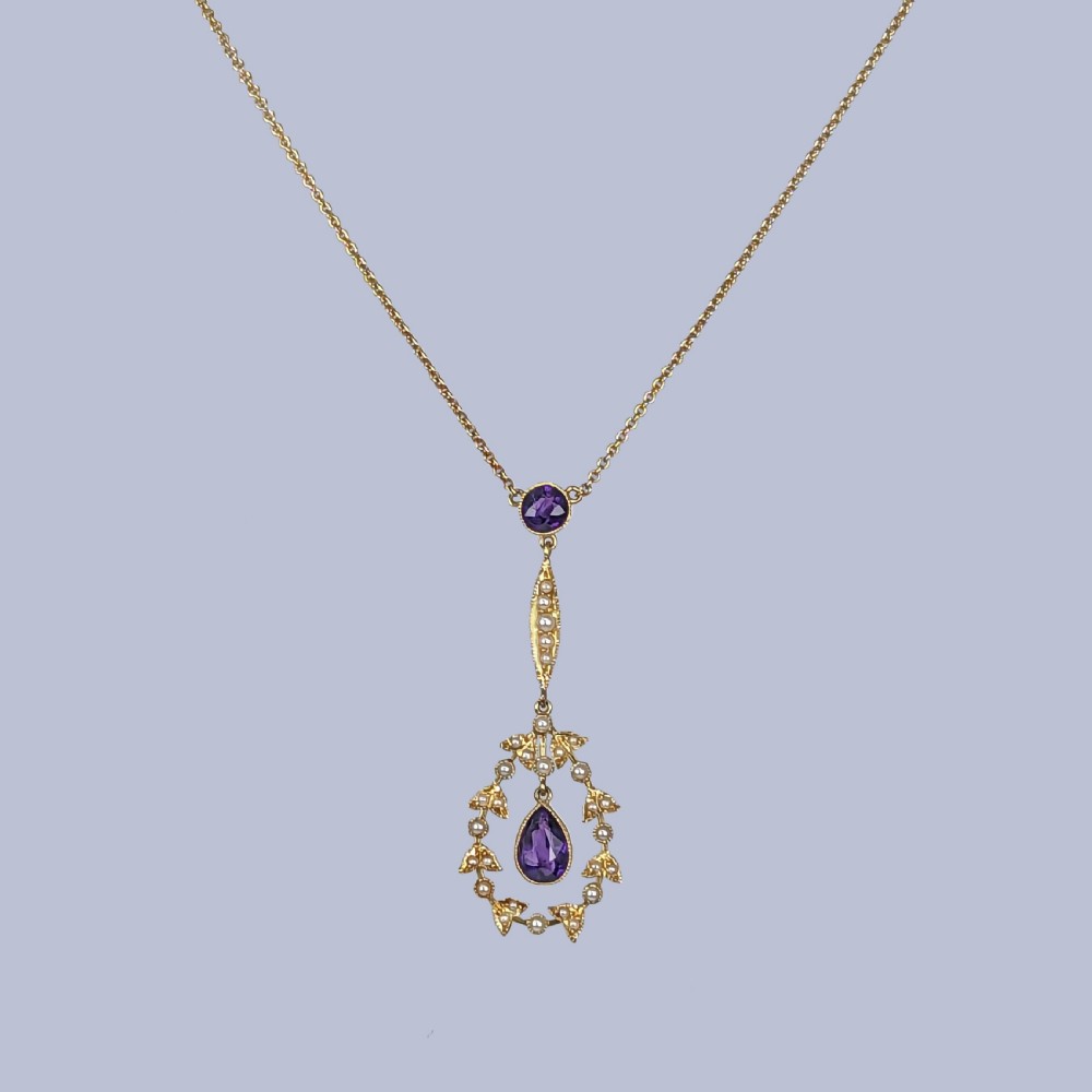 A Victorian gold pendant necklace featuring a central teardrop amethyst suspended within a seed pearl foliate wreath, attached to a gold chain. View VIII