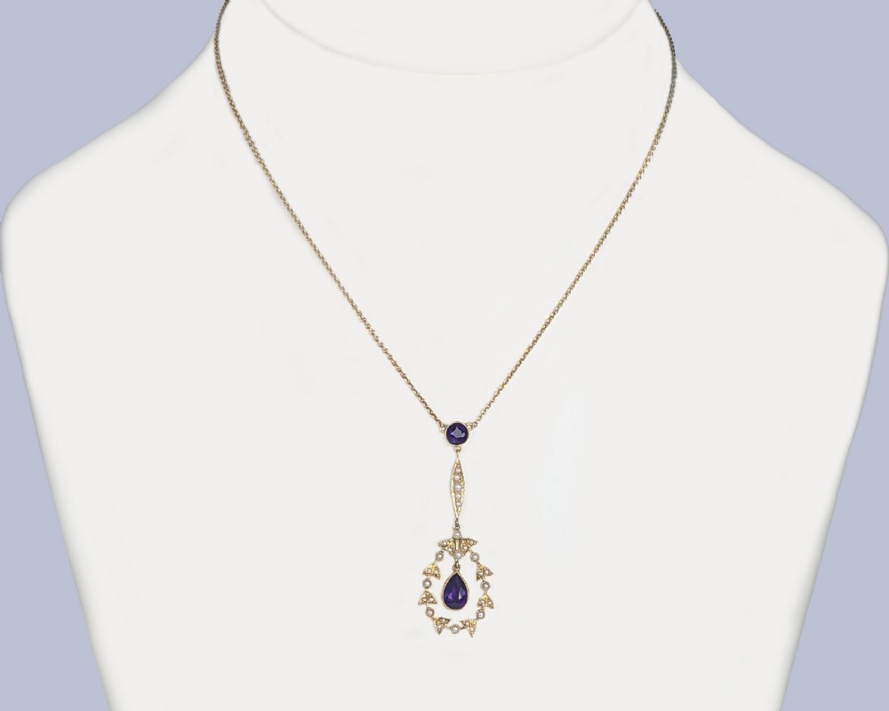 A Victorian gold pendant necklace featuring a central teardrop amethyst suspended within a seed pearl foliate wreath, attached to a gold chain. View XI