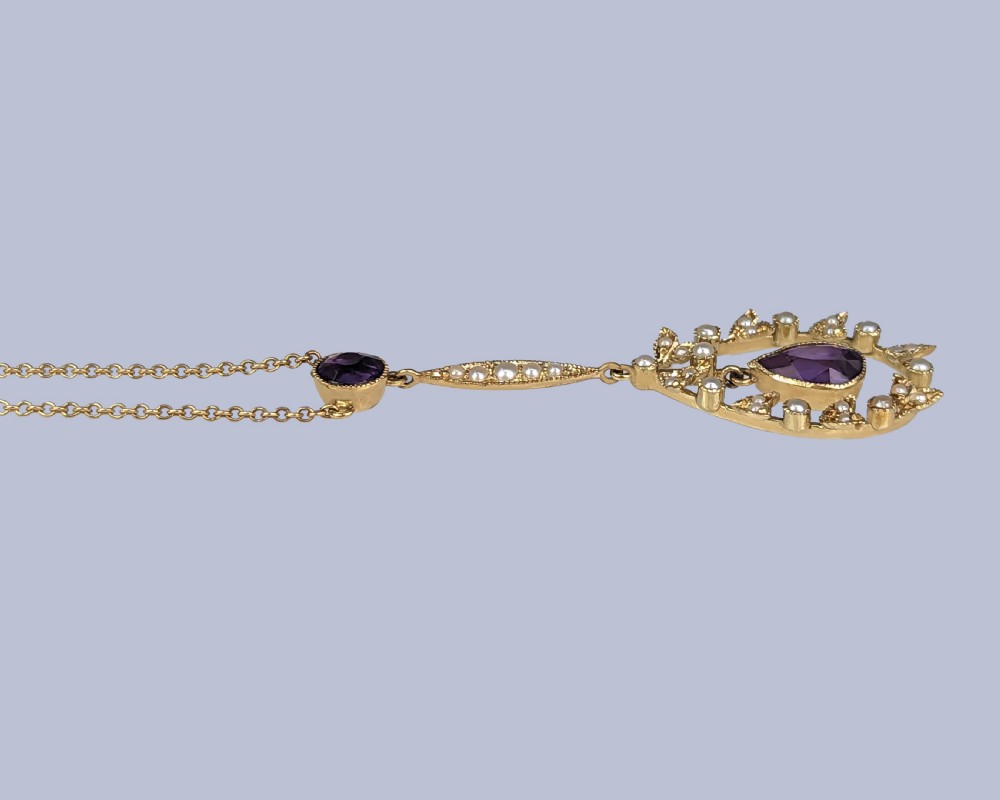 A Victorian gold pendant necklace featuring a central teardrop amethyst suspended within a seed pearl foliate wreath, attached to a gold chain. View XII