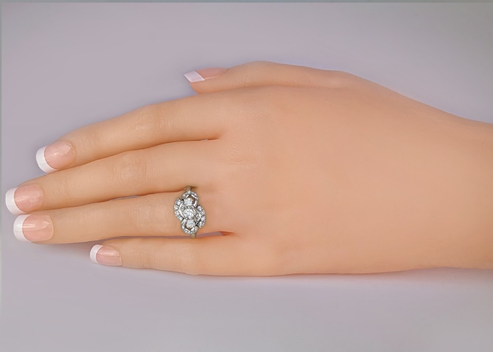 An 18ct white gold 1930s cluster ring featuring three central brilliant-cut diamonds flanked by curved diamond accents. View VIII