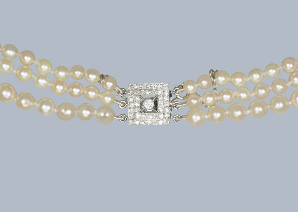 An Art Deco triple-strand cultured pearl necklace with a square geometric clasp set with brilliant diamonds. View X