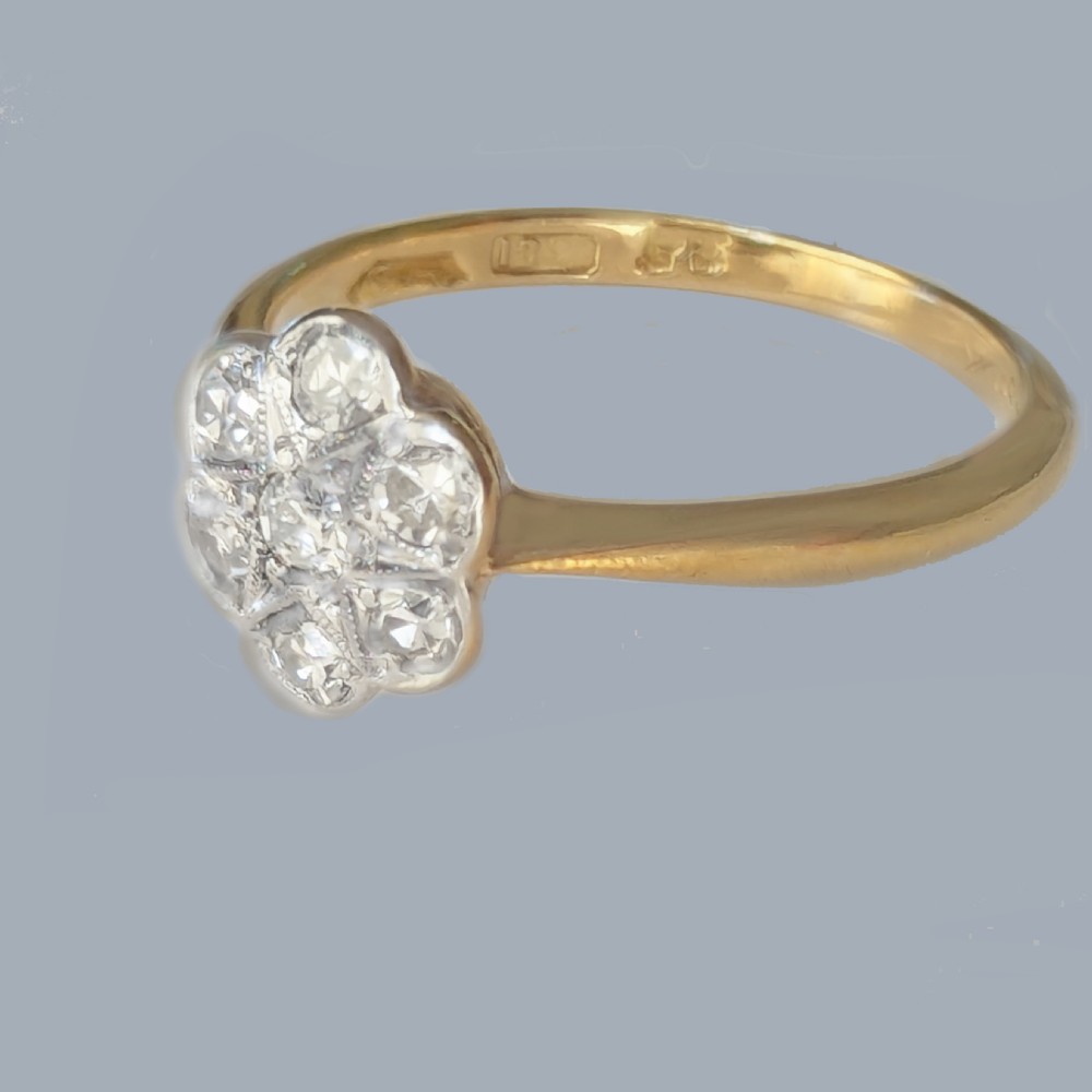 A 1920s diamond daisy cluster ring featuring seven round diamonds in a white metal floral setting on a yellow gold band. View IV