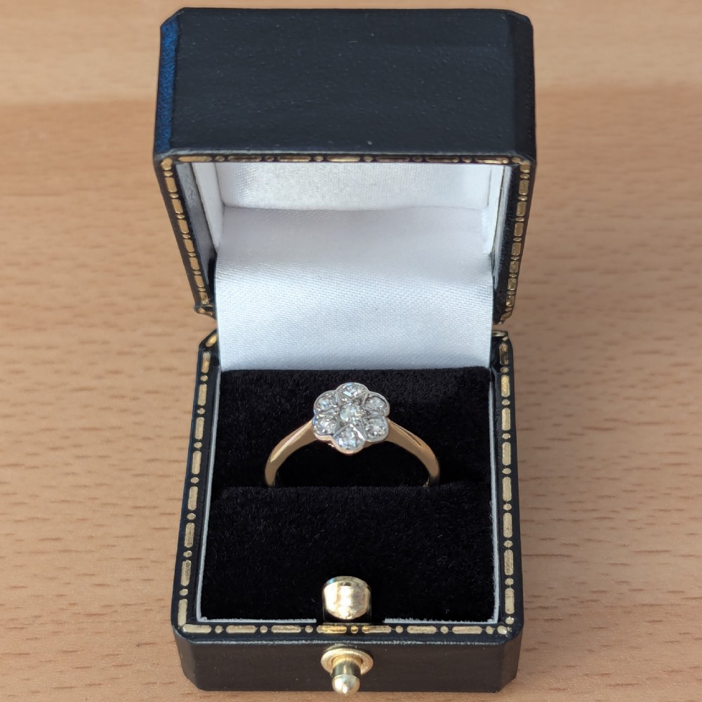 A 1920s diamond daisy cluster ring featuring seven round diamonds in a white metal floral setting on a yellow gold band. View VI