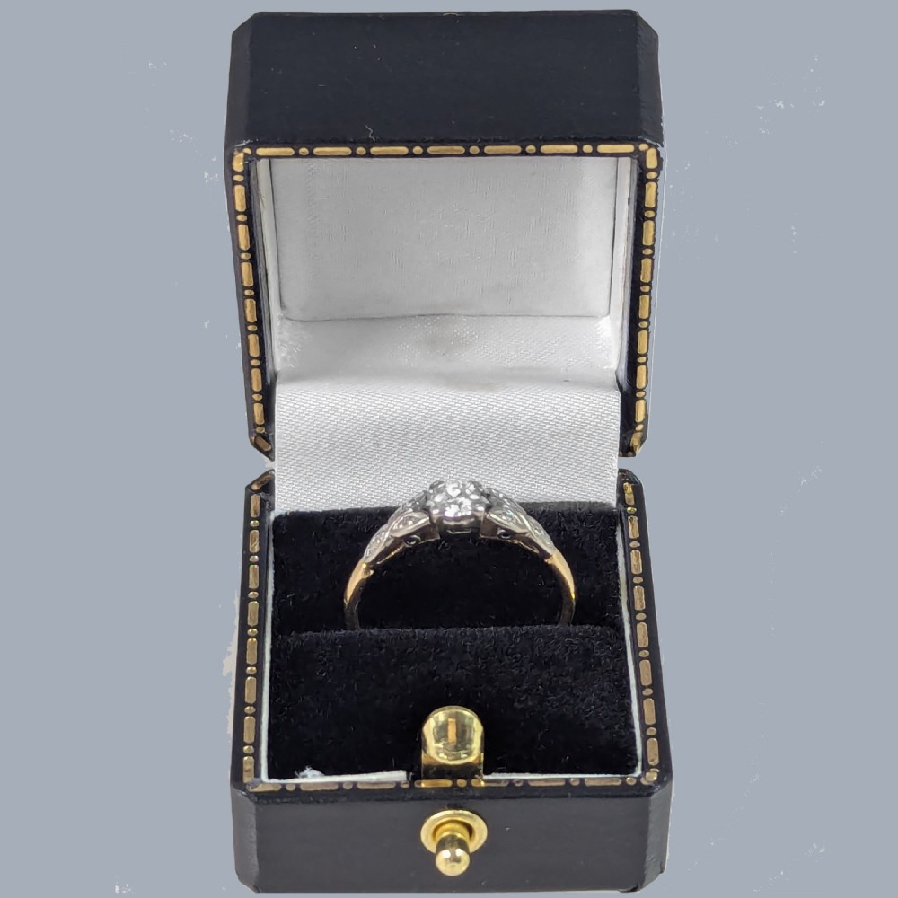 An Edwardian solitaire ring featuring a central round diamond in a platinum setting with diamond leaf shoulders on an 18ct yellow gold band. View VIII