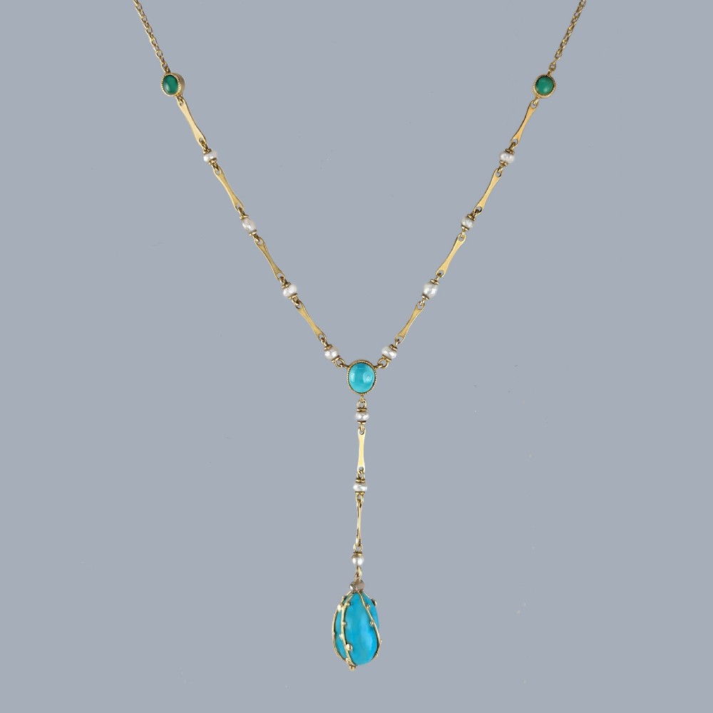 An Arts and Crafts 15ct gold necklace featuring elongated bar links set with small pearls, leading to a central turquoise cabochon and a dangling caged turquoise drop pendant.