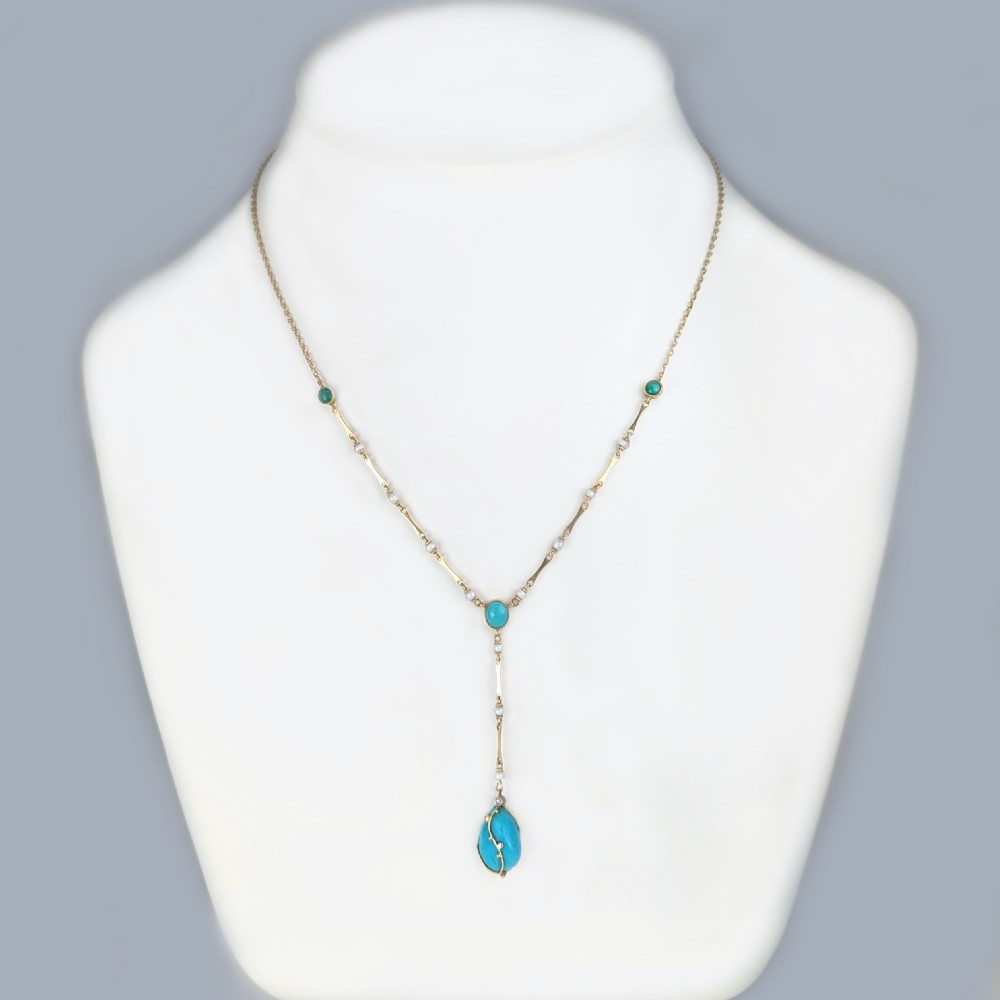 An Arts and Crafts 15ct gold necklace featuring elongated bar links set with small pearls, leading to a central turquoise cabochon and a dangling caged turquoise drop pendant. View II