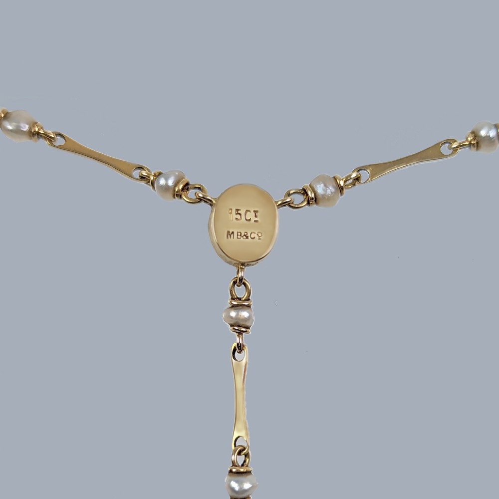 An Arts and Crafts 15ct gold necklace featuring elongated bar links set with small pearls, leading to a central turquoise cabochon and a dangling caged turquoise drop pendant. View IV