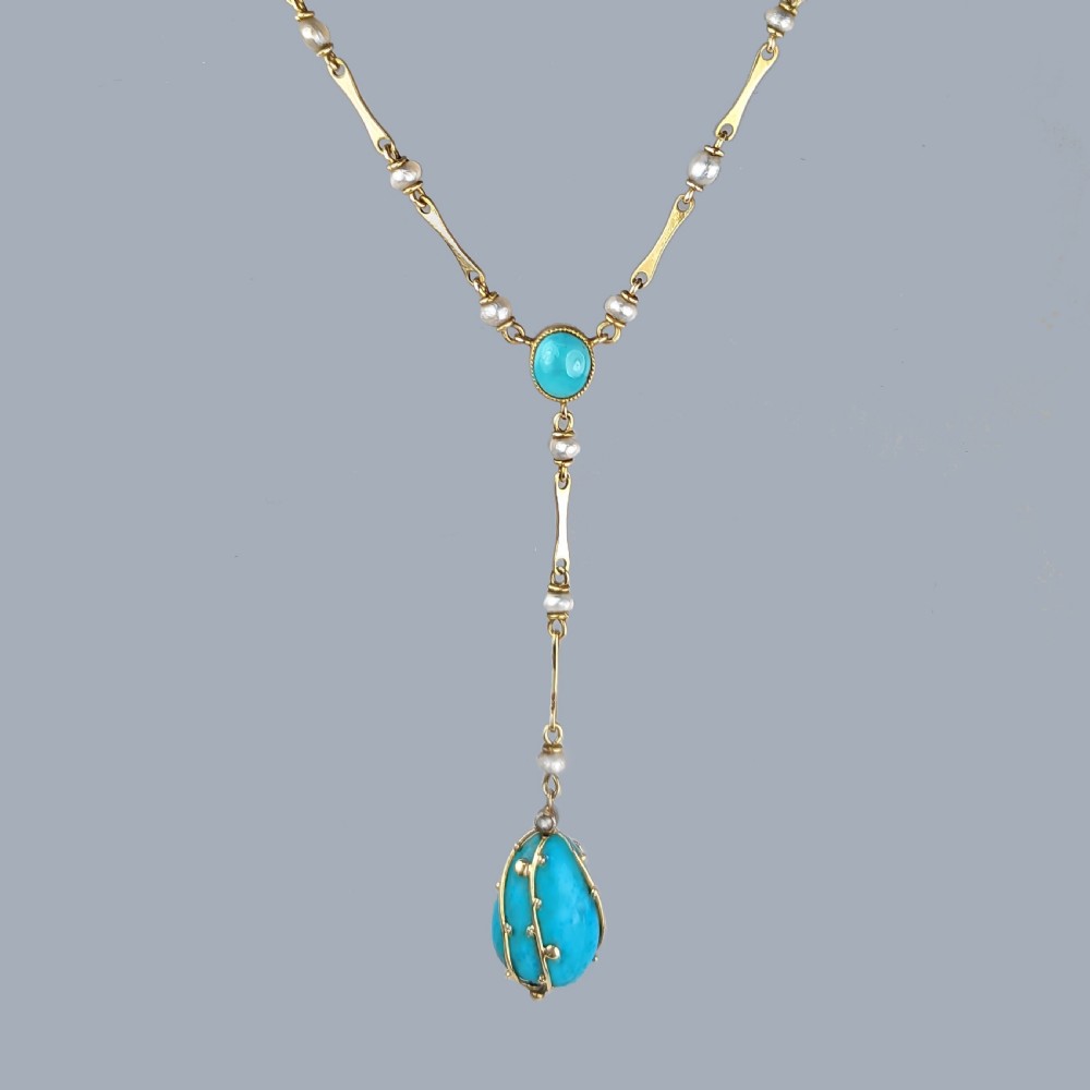 An Arts and Crafts 15ct gold necklace featuring elongated bar links set with small pearls, leading to a central turquoise cabochon and a dangling caged turquoise drop pendant. View XI