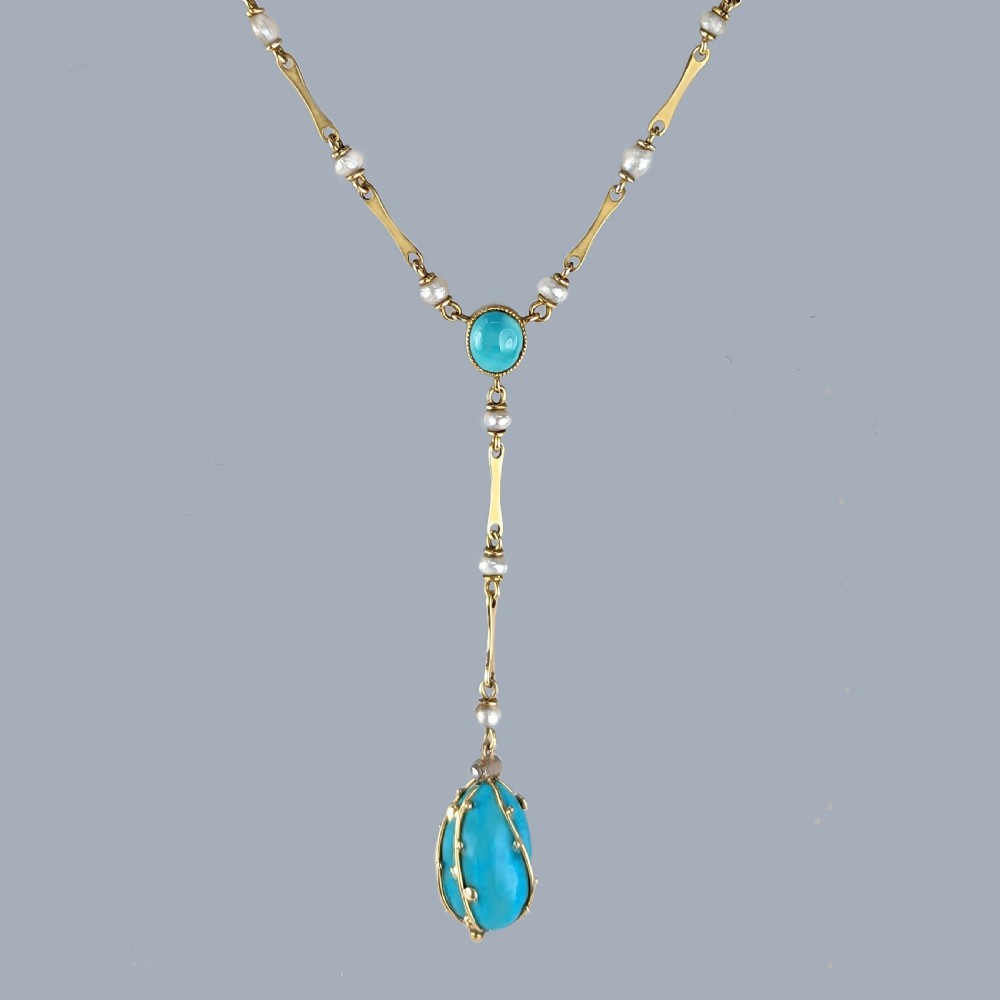 An Arts and Crafts 15ct gold necklace featuring elongated bar links set with small pearls, leading to a central turquoise cabochon and a dangling caged turquoise drop pendant. View XIII