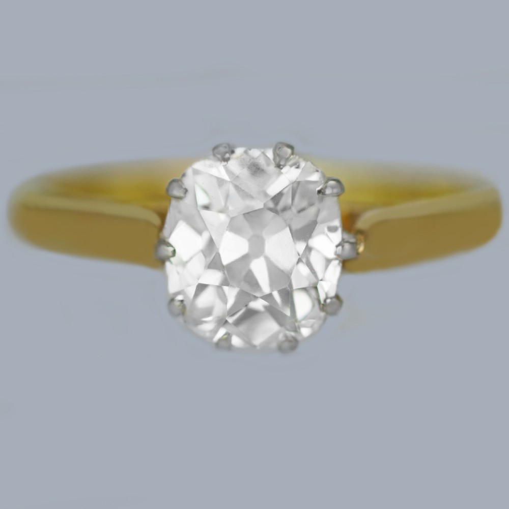 A vintage 18ct yellow gold solitaire ring featuring a 1.3-carat old cushion-cut diamond held in white metal claw settings.