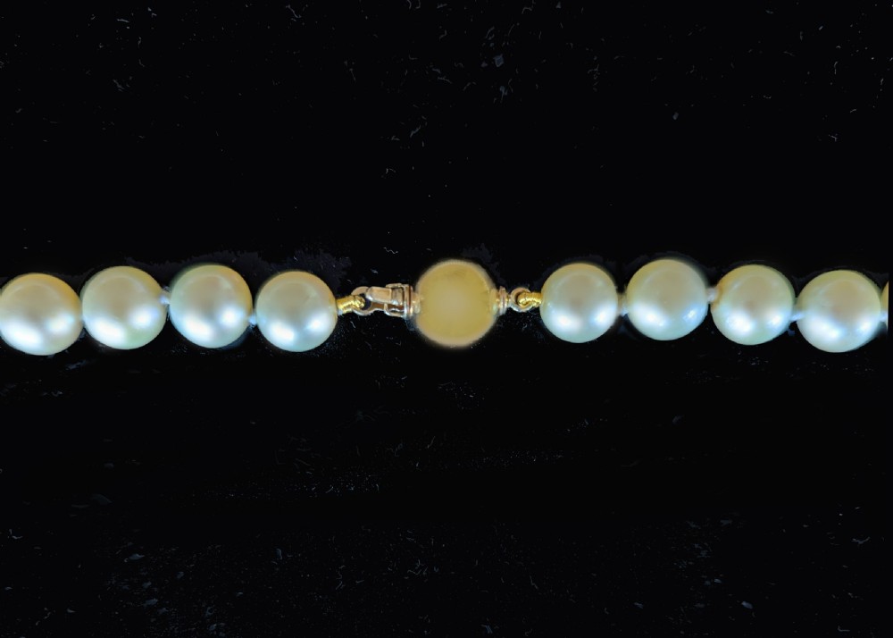 A long vintage cultured pearl sautoir necklace layered in multiple loops around a neck, featuring a small spherical gold clasp. View VI