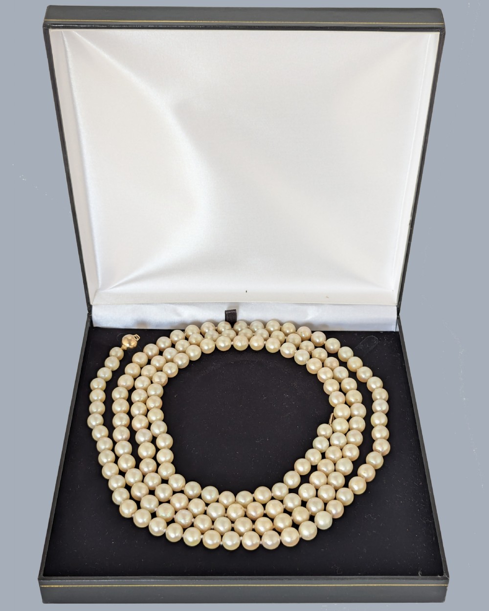 A long vintage cultured pearl sautoir necklace layered in multiple loops around a neck, featuring a small spherical gold clasp. View XI