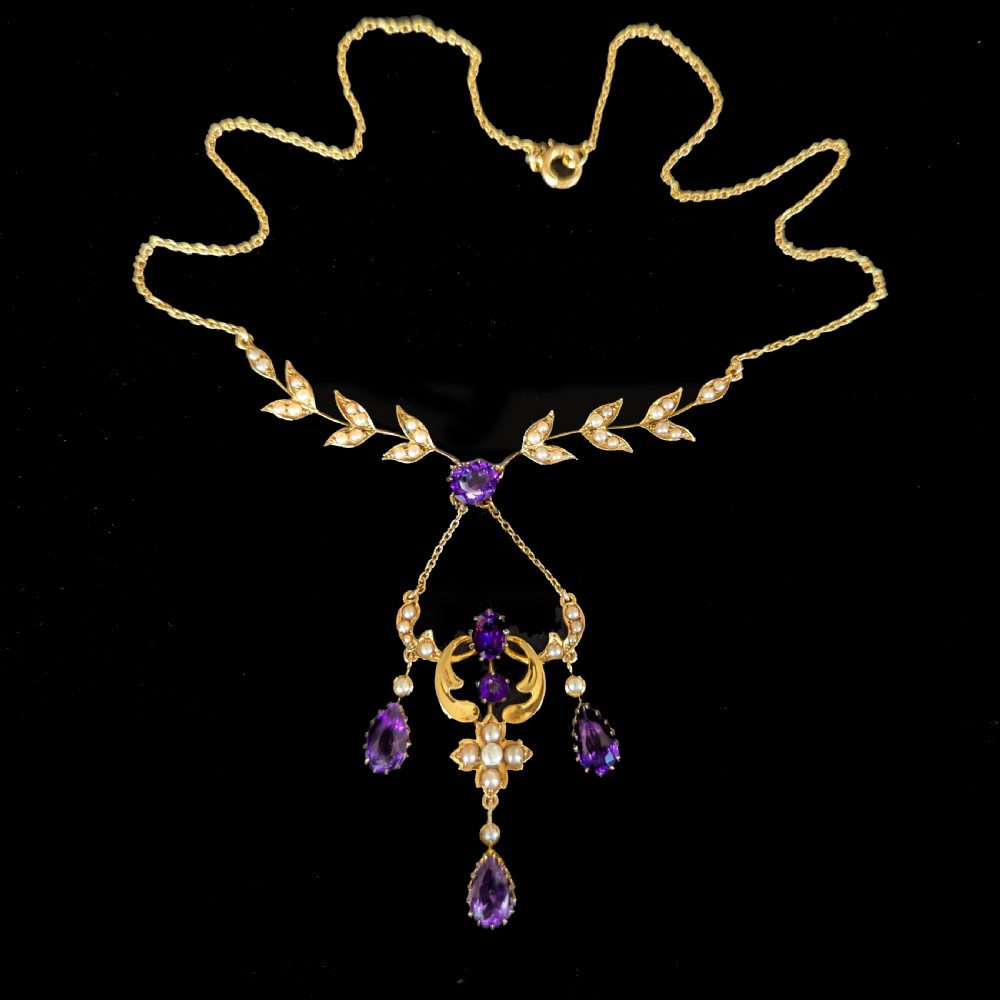 An Edwardian 15ct yellow gold necklace featuring foliate leaf motifs set with seed pearls and an openwork pendant with faceted purple amethysts. View III