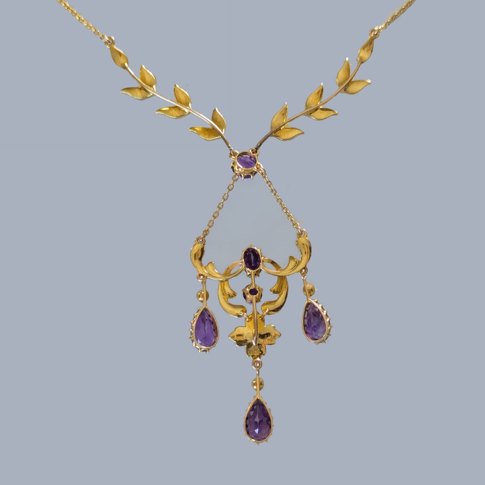 An Edwardian 15ct yellow gold necklace featuring foliate leaf motifs set with seed pearls and an openwork pendant with faceted purple amethysts. View VII