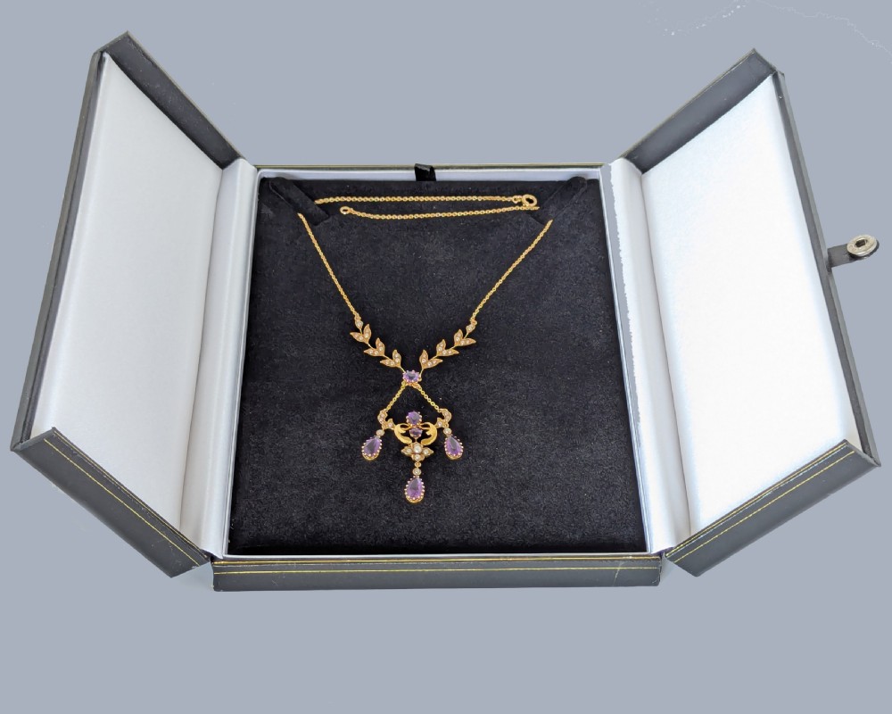 An Edwardian 15ct yellow gold necklace featuring foliate leaf motifs set with seed pearls and an openwork pendant with faceted purple amethysts. View VIII