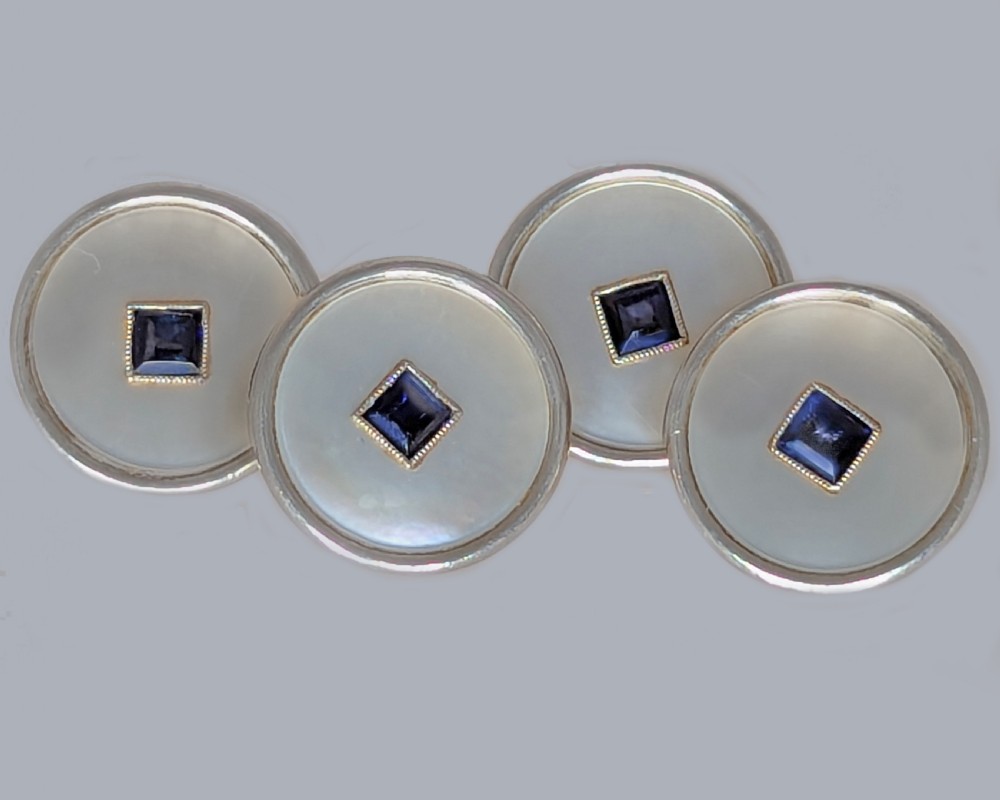 Four round double-sided cufflinks made from mother of pearl discs, each set with a central square blue sapphire framed in platinum and gold. View VII