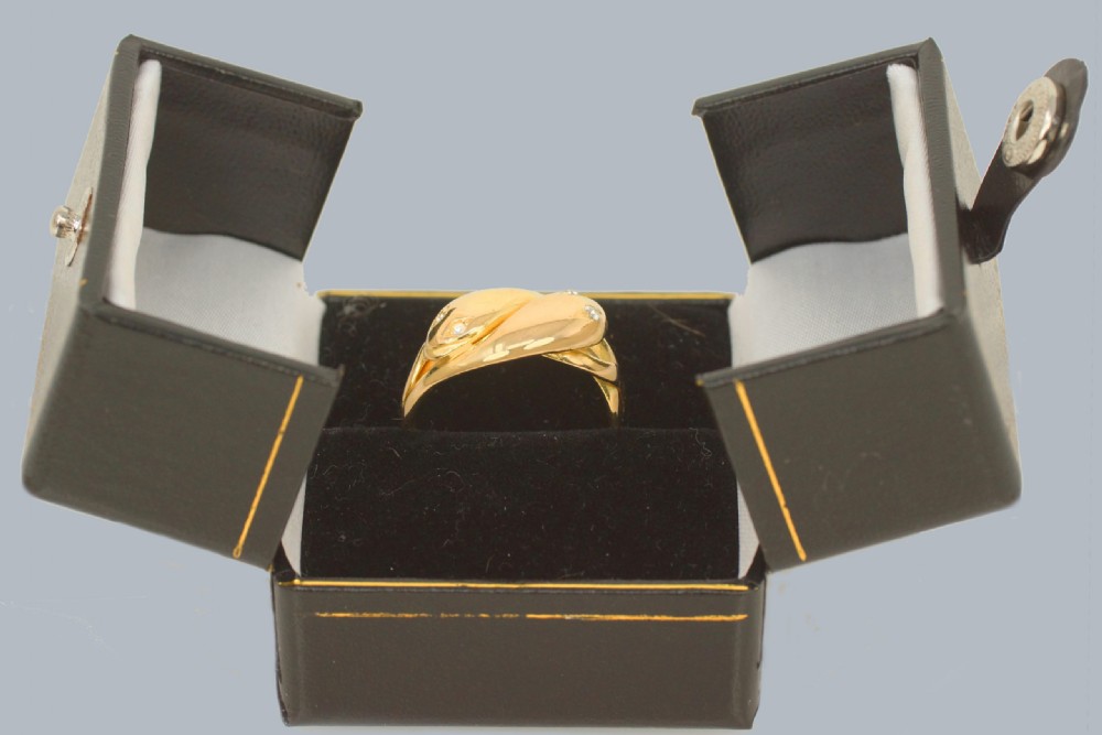 An 18ct yellow gold double snake ring featuring two intertwined serpent heads set with small rose-cut diamond eyes. View X