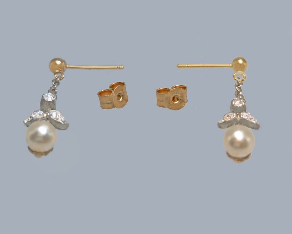 A pair of Edwardian drop earrings featuring gold studs connected by fine chain links to diamond-set foliate motifs and single white pearl drops. View V