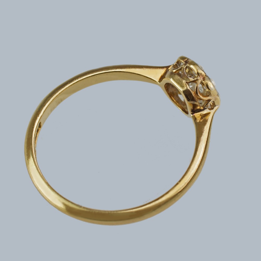 An Edwardian diamond cluster ring featuring a central old European cut diamond surrounded by eight smaller diamonds set in platinum on a yellow gold band. View VIII