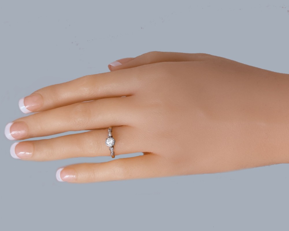 An antique 1920s diamond solitaire ring with a round cut central diamond set in platinum with geometric shoulders on an 18ct yellow gold band. View IV