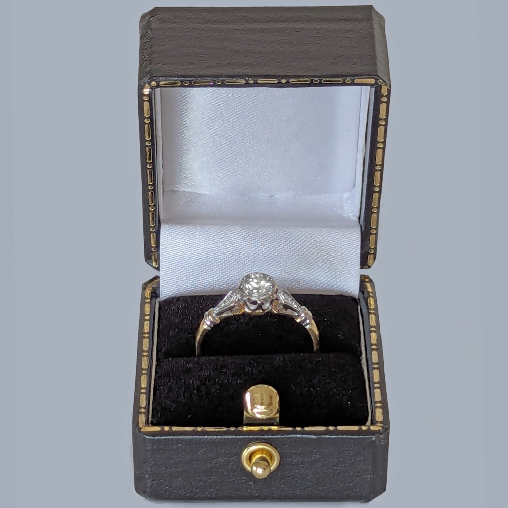 An antique 1920s diamond solitaire ring with a round cut central diamond set in platinum with geometric shoulders on an 18ct yellow gold band. View VII