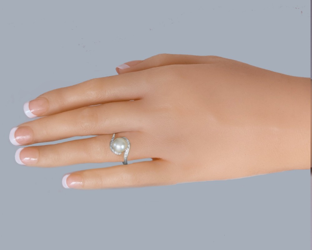 A 1950s 18ct white gold bypass ring featuring a central cream pearl enveloped by a swirling band set with small round diamonds. View X