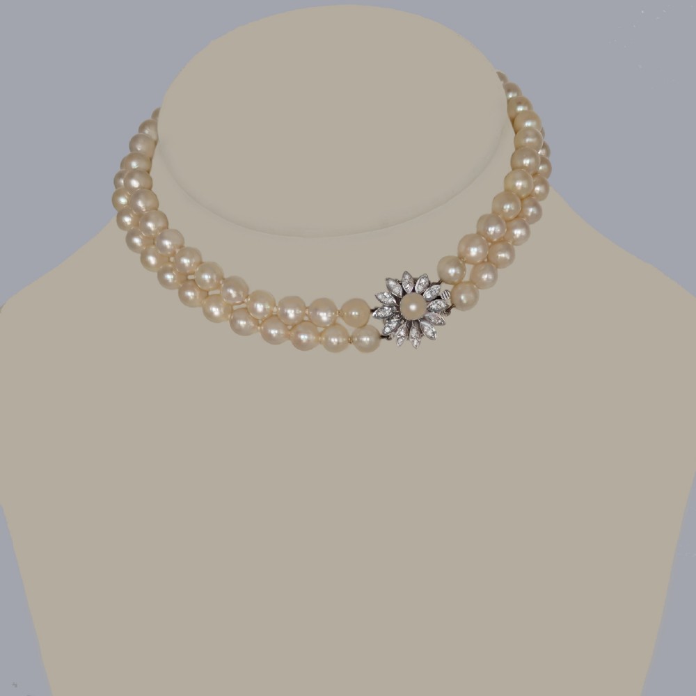 A double-strand choker necklace composed of cream-coloured pearls connected by a white gold floral daisy clasp set with diamonds. View IV