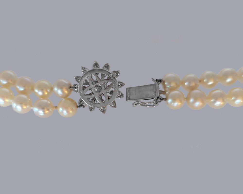 A double-strand choker necklace composed of cream-coloured pearls connected by a white gold floral daisy clasp set with diamonds. View VI
