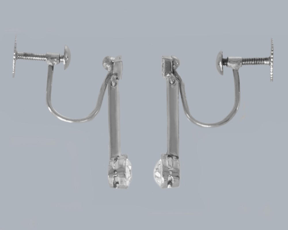 A pair of Edwardian 18ct white gold drop earrings featuring pear-shaped diamonds suspended from linear knife-edge bars and diamond-shaped top studs. View III
