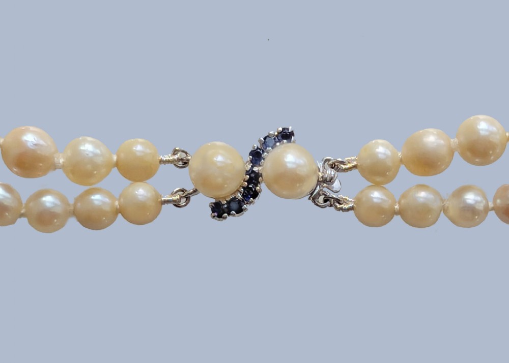 A double-strand cultured pearl necklace featuring uniform cream pearls arranged in two parallel rows with a sapphire-set gold clasp. View II