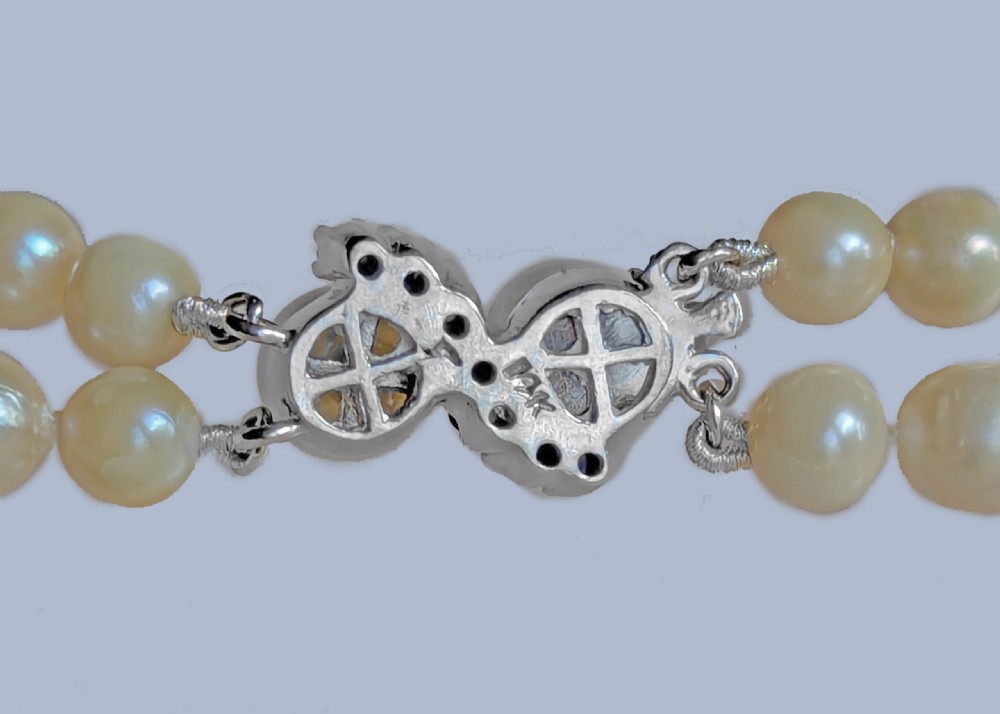 A double-strand cultured pearl necklace featuring uniform cream pearls arranged in two parallel rows with a sapphire-set gold clasp. View IX
