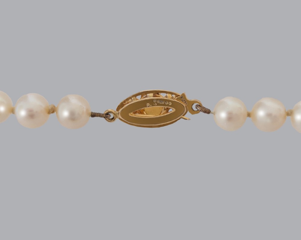 A long hand-knotted strand of cream cultured pearls featuring an oval filigree 9ct yellow gold clasp. View IV