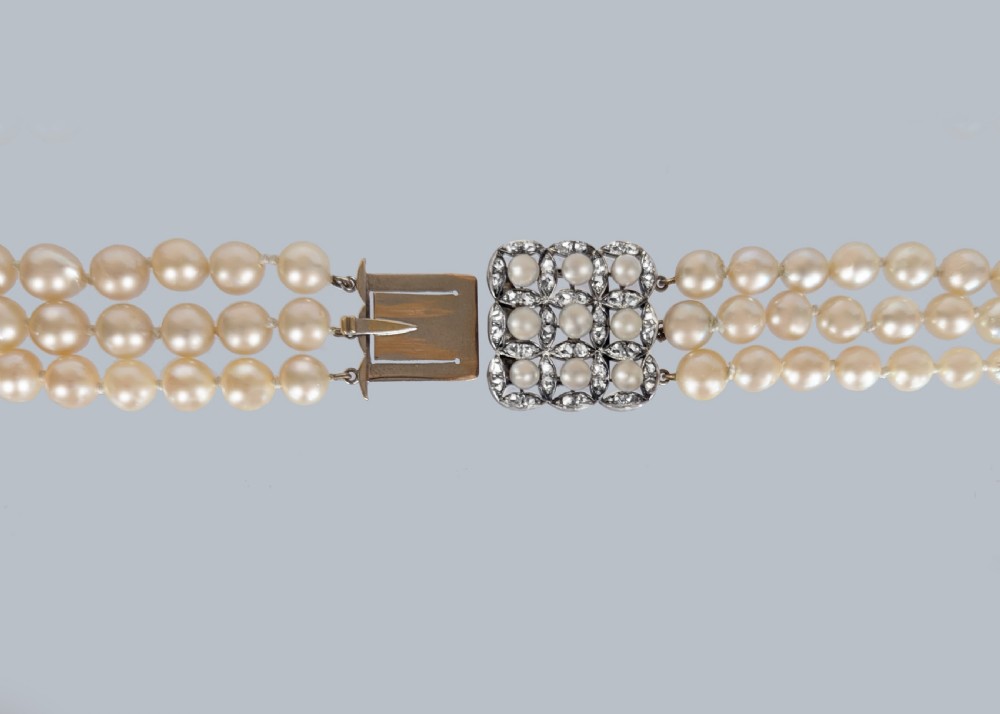 An Art Deco triple-strand cream pearl necklace featuring an ornate square clasp set with rose-cut diamonds and central pearl accents. View IX