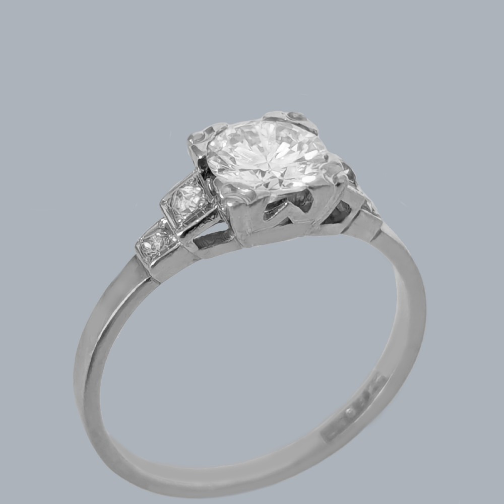 A platinum solitaire ring featuring a central round brilliant diamond held in a claw setting with stepped diamond shoulders. View II