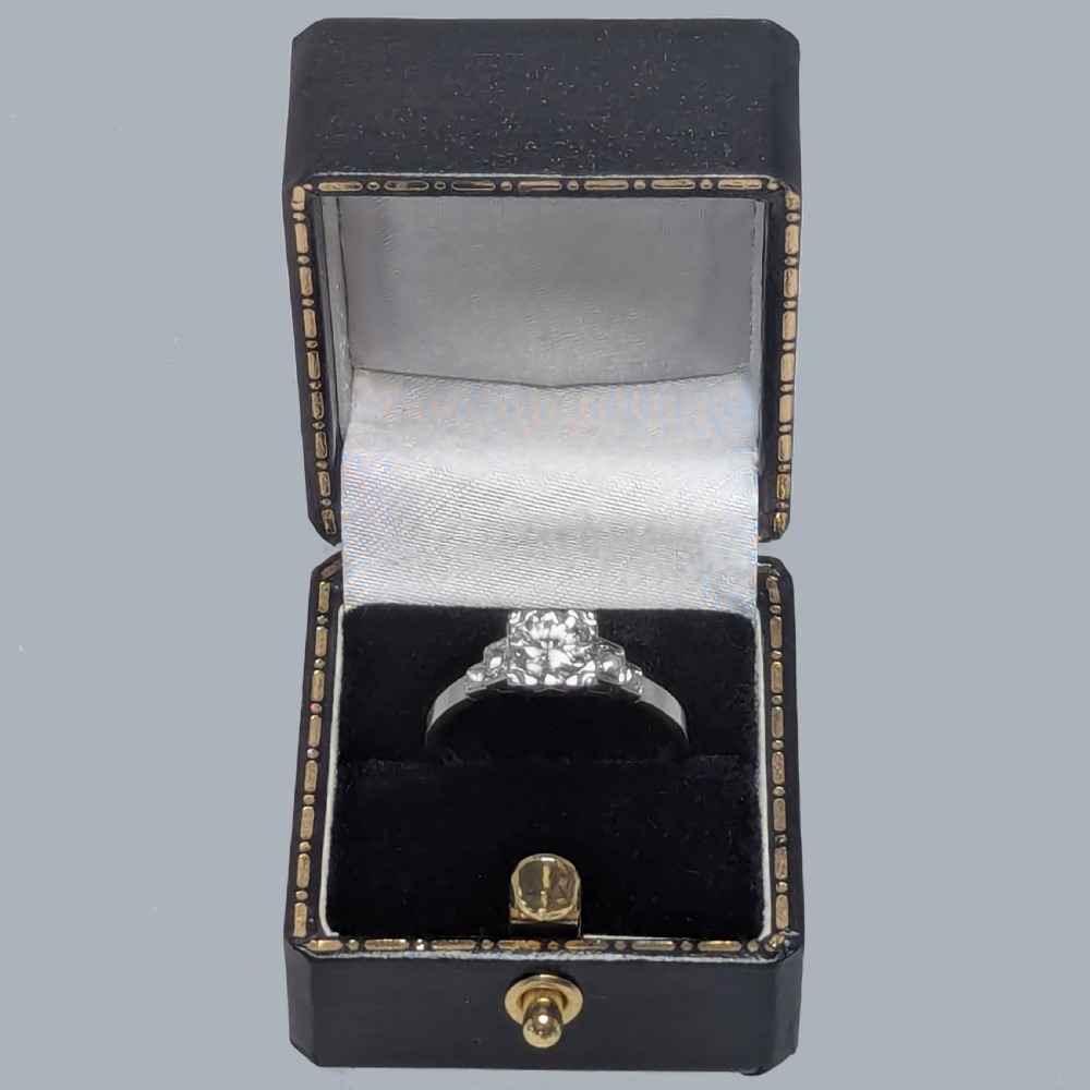 A platinum solitaire ring featuring a central round brilliant diamond held in a claw setting with stepped diamond shoulders. View VIII